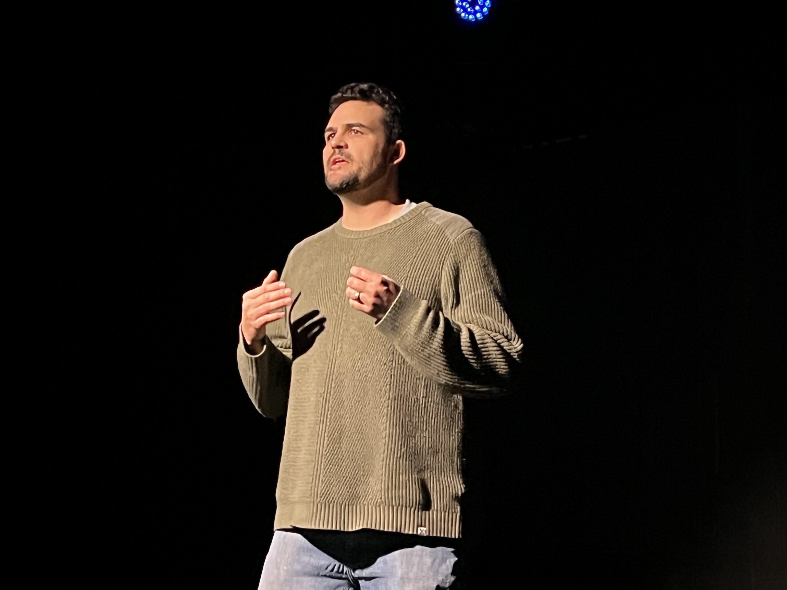 Man on stage speaking in spotlight