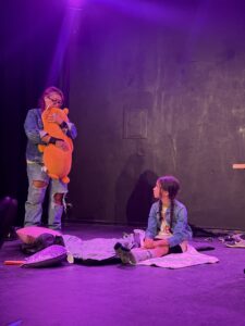 Actors on stage with purple lighting.