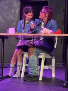 Two people in denim talk at a table.