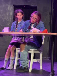 Two people in denim jackets performing on stage.