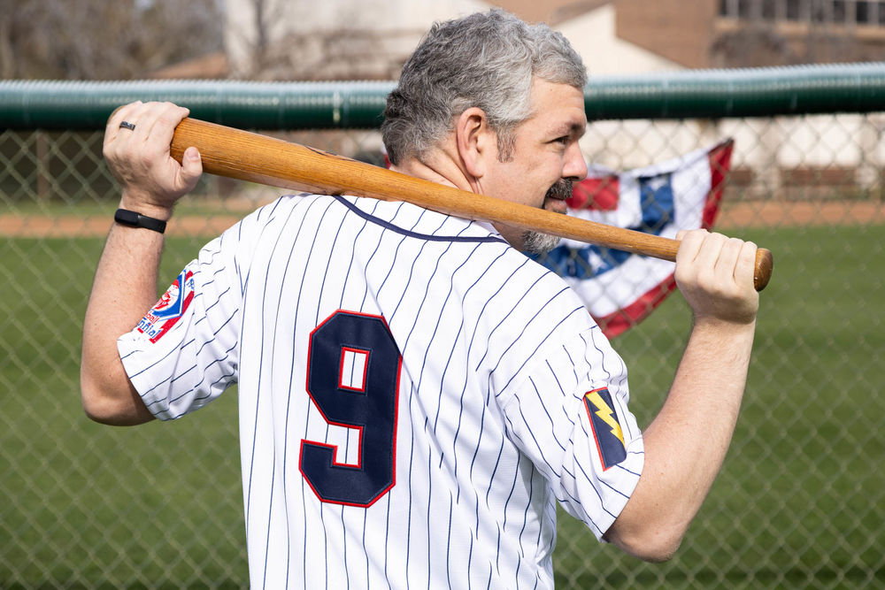 Man holding baseball bat, wearing striped jersey.