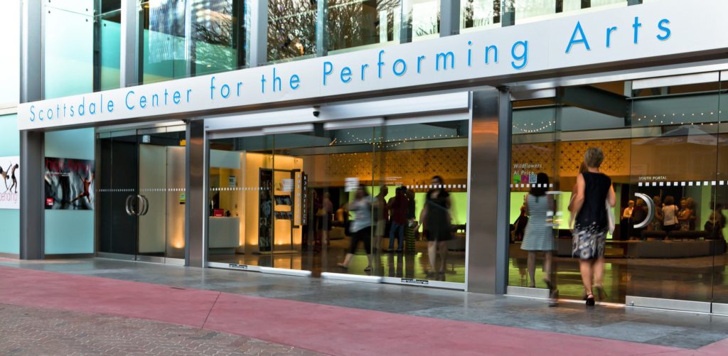 Entrance of performing arts center with people.